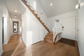 Ein modernes Interieur mit einer Holztreppe, weißen Wänden und einem Flur, der in einen anderen Raum führt.