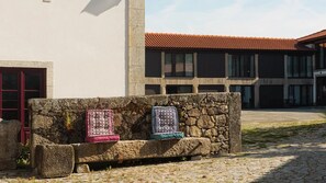 Un banc de pedra amb llençols davant d'un edifici amb teulades vermelles i una paret de pedra.