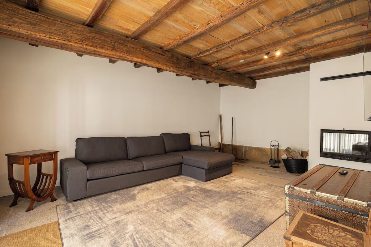 A cozy living room with a sectional sofa, a small wooden table, and a rustic ceiling.