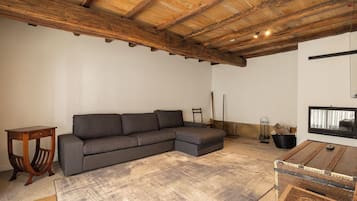 A cozy living room with a sectional sofa, a small wooden table, and a rustic ceiling.