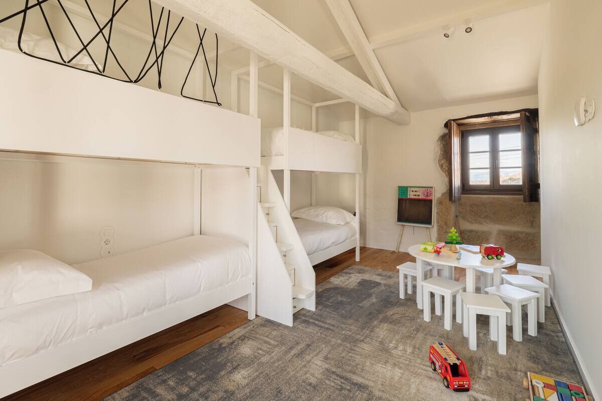 A room with bunk beds, a small table with toys, and a window.