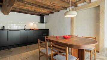 Una cocina moderna con armarios oscuros, una mesa de comedor de madera y una lámpara colgante.
