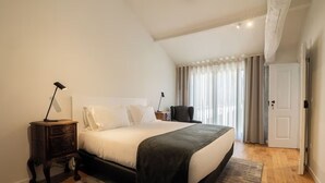 A bedroom with a large bed, a bedside table, a lamp, a chair, and a window with curtains. - Countryside Getaway with Pool Access Near Local Attractions - Bom Jesus do Monte (Braga)
