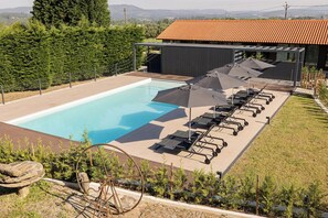 A swimming pool with lounge chairs and umbrellas, surrounded by greenery and a building with a tiled roof. - Relaxing Rural Escape - Junior Suite with Pool Access and Scenic Views (Braga)