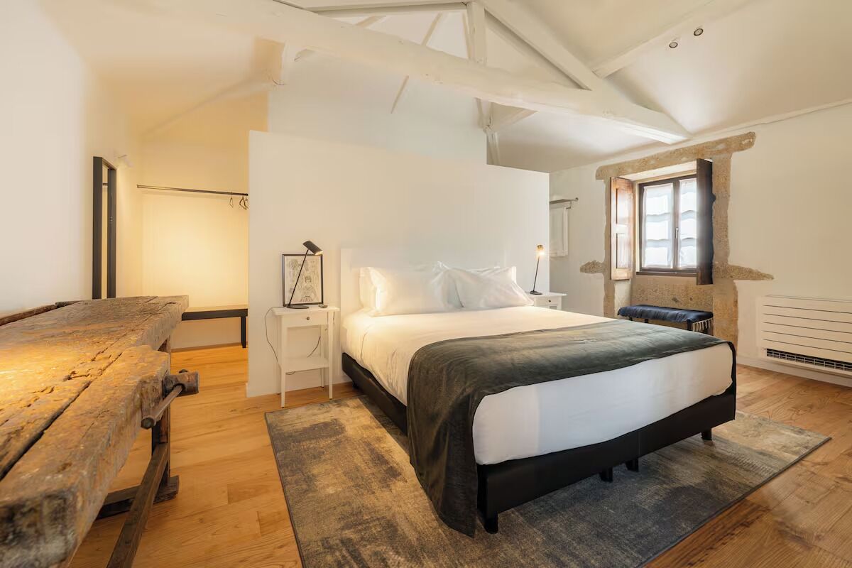 A bedroom with a bed, bedside tables, a bench, and a window.