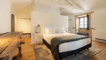 A bedroom with a bed, bedside tables, a bench, and a window.