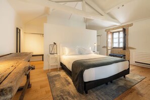 A bedroom with a bed, bedside tables, a bench, and a window.