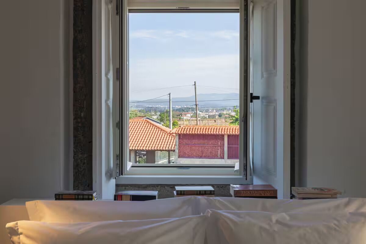 A bedroom with a window overlooking a residential area.