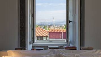 A bedroom with a window overlooking a residential area.