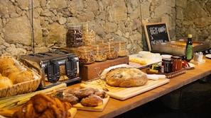 A breakfast buffet with various food items, including bread, pastries, and condiments. - Comfortable Rural Getaway with Pool Access, Rustic Charm, and Scenic Views (Braga)