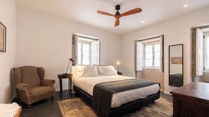 Un dormitorio con una cama grande, una silla, un escritorio y un ventilador de techo.