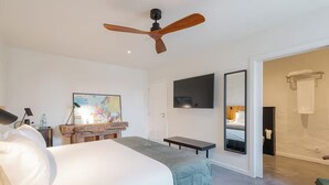 A modern hotel room with a large bed, a ceiling fan, a flat-screen TV, a wooden dresser, and a bathroom visible through an open door. - Tranquil Rural Getaway with Pool Access and Rustic Atmosphere - Near Braga (Braga)