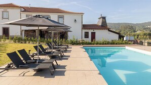 A poolside area with lounge chairs and umbrellas, a swimming pool, and a building with a tiled roof. - Tranquil Rural Getaway with Pool Access and Rustic Atmosphere - Near Braga (Braga)