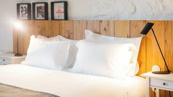 A neatly made bed with white linens, a wooden headboard, and a bedside table with a lamp.