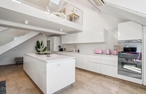 A modern kitchen with a central island, upper-level seating, and a built-in oven. - AN EXCEPTIONAL BLEND OF ELEGANCE, COMFORT WITH BREATHTAKING ROOFTOP TERRACES (Zürich)