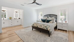 A bedroom with a bed, bedside tables, a ceiling fan, and a window with blinds. - Riverfront Retreat with Pool, Spa & Dock (Estero)