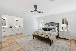 A bedroom with a bed, bedside tables, a ceiling fan, and a window with blinds. - Riverfront Retreat with Pool, Spa & Dock (Estero)