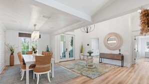 A spacious dining area with a white table and chairs, a chandelier, and a round mirror on the wall. - Riverfront Retreat with Pool, Spa & Dock (Estero)