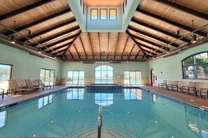 An indoor swimming pool with a high ceiling, lounge chairs, and large windows. - Gulf - Front Luxury in Orange Beach l Stunning Views + Resort Amenities (Orange Beach)