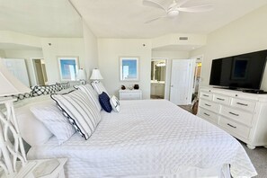 Ein Schlafzimmer mit einem Bett, Nachttischen, einem Fernseher, einer Kommode und einem Deckenventilator.