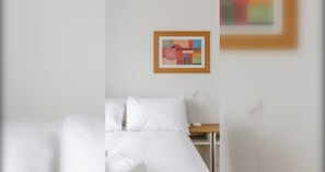 A hotel room with a bed, a nightstand, and a framed abstract painting on the wall. - Large Modern 4 BDR Home Near ExCel London (Greater London)