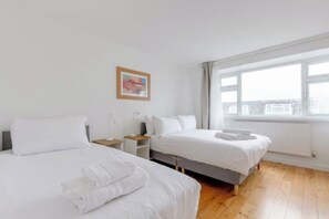 A hotel room with two beds, a window, and a radiator. - Large Modern 4 BDR Home Near ExCel London (Greater London)