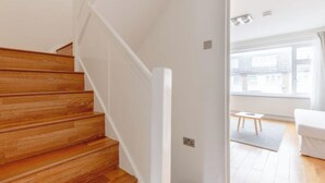 A staircase with wooden steps leading to a white wall. - Large Modern 4 BDR Home Near ExCel London (Greater London)