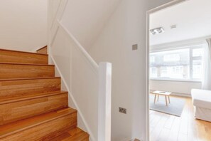 A staircase with wooden steps leading to a white wall. - Large Modern 4 BDR Home Near ExCel London (Greater London)