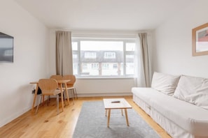 A minimalist living room with a sofa, a small table, and two chairs. - Large Modern 4 BDR Home Near ExCel London (Greater London)