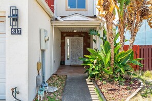 A house with a number 217 sign, a front door, a small porch, and a garden with a banana tree. - 217 Cherie Down Ln (Cape Canaveral)