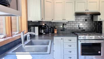 A modern kitchen with a stainless steel sink, a gas stove, and white cabinetry.