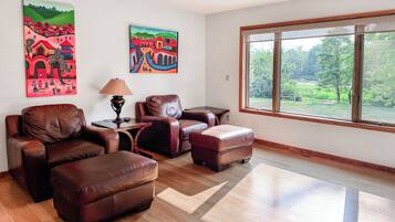 A living room with leather furniture, a lamp, and two paintings on the wall.
