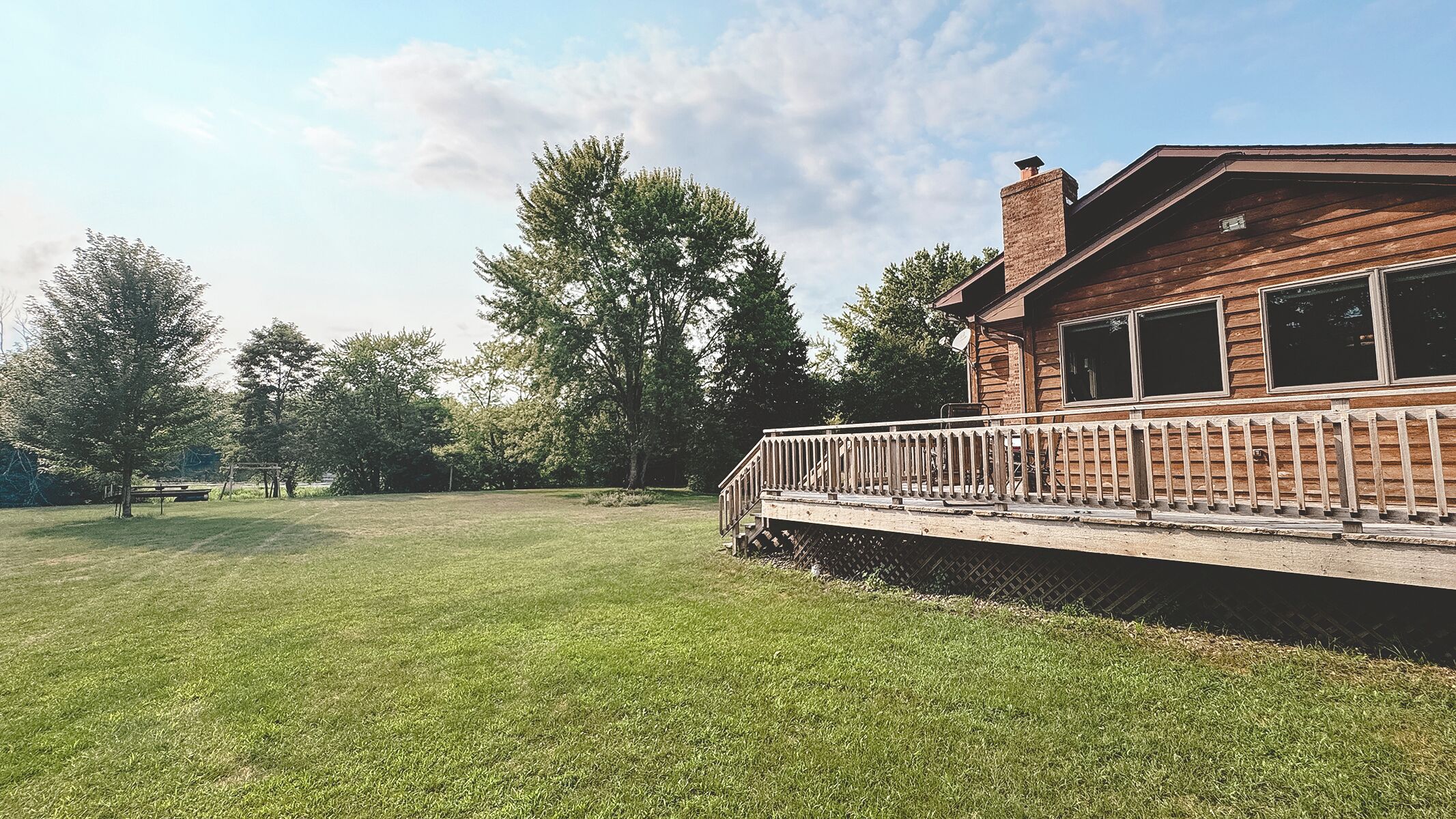 A wooden cabin with a covered deck and a grassy yard.