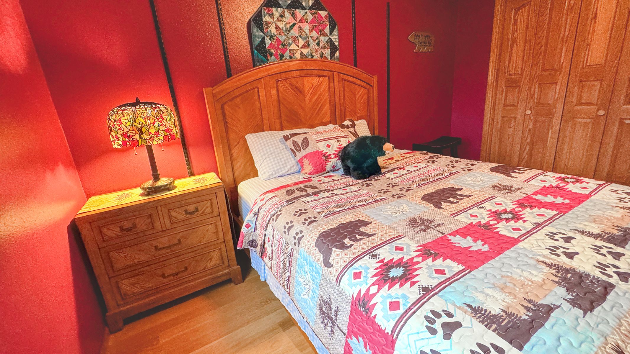 Un dormitorio con una cama de madera, una mesita de noche con lámpara y un edredón con estampados de animales.