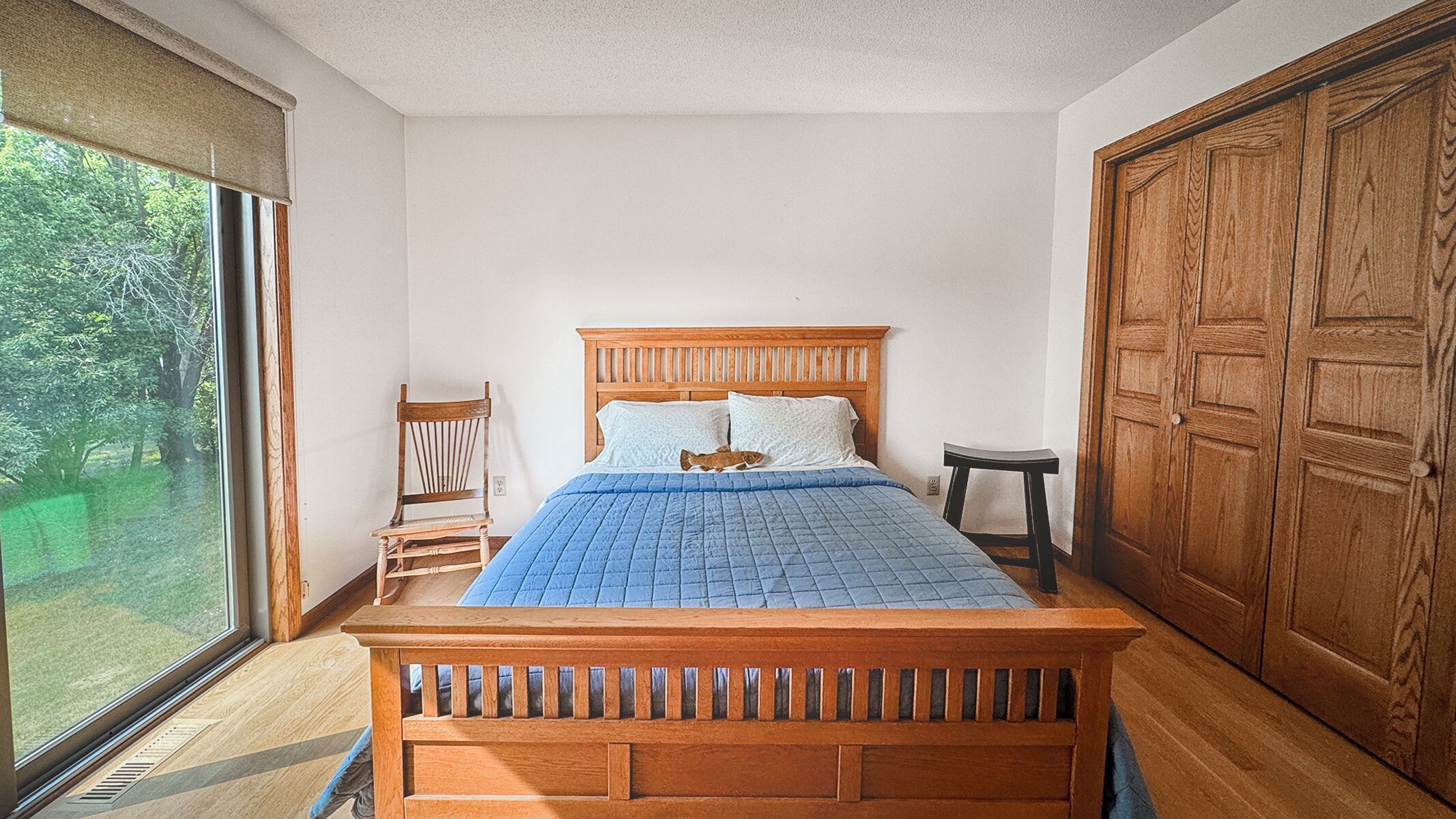 A bedroom with a wooden bed, a chair, a small stool, and a wardrobe.