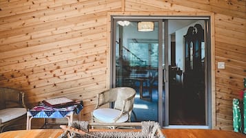 A wooden interior with a ceiling fan, a woven rug, and a view through a glass door to another room.