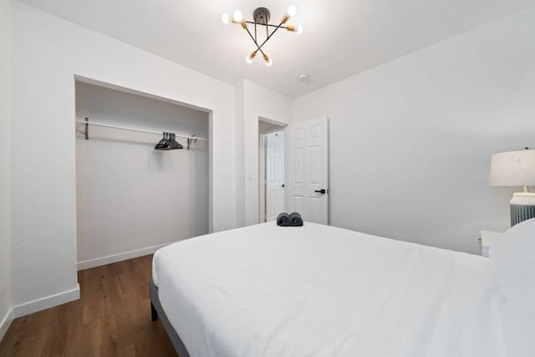 Un dormitorio con cama, armario, puerta y lámpara en el techo.