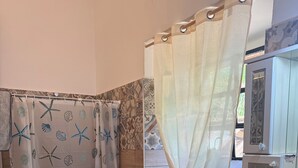 Une salle de bain équipée de toilettes, d’un bidet, d’un lavabo et d’un rideau de douche orné d’un motif d’étoile de mer.