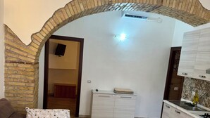 Une pièce comprenant un lit, un canapé, une commode et un mur en briques en forme d’arc.