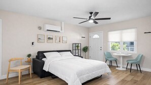 A bedroom with a bed, a ceiling fan, a window, and a small table with chairs. - 221 Madison Ave - Unit B (Cape Canaveral)