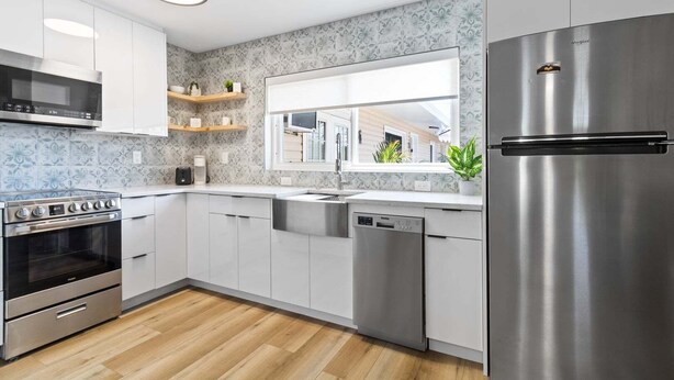 A modern kitchen with stainless steel appliances, a dishwasher, and a window overlooking a residential area. - 221 Madison Ave - Unit B (Cape Canaveral)