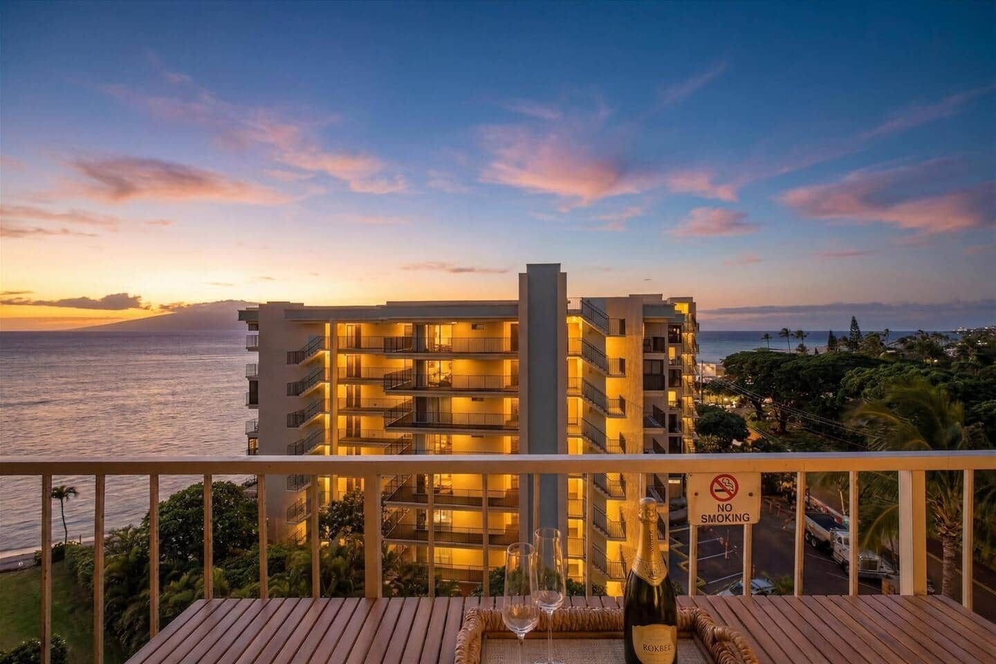 Hotel met balkon, uitzicht op een zonsondergang en de oceaan, met een 'Roken verboden'-bordje.