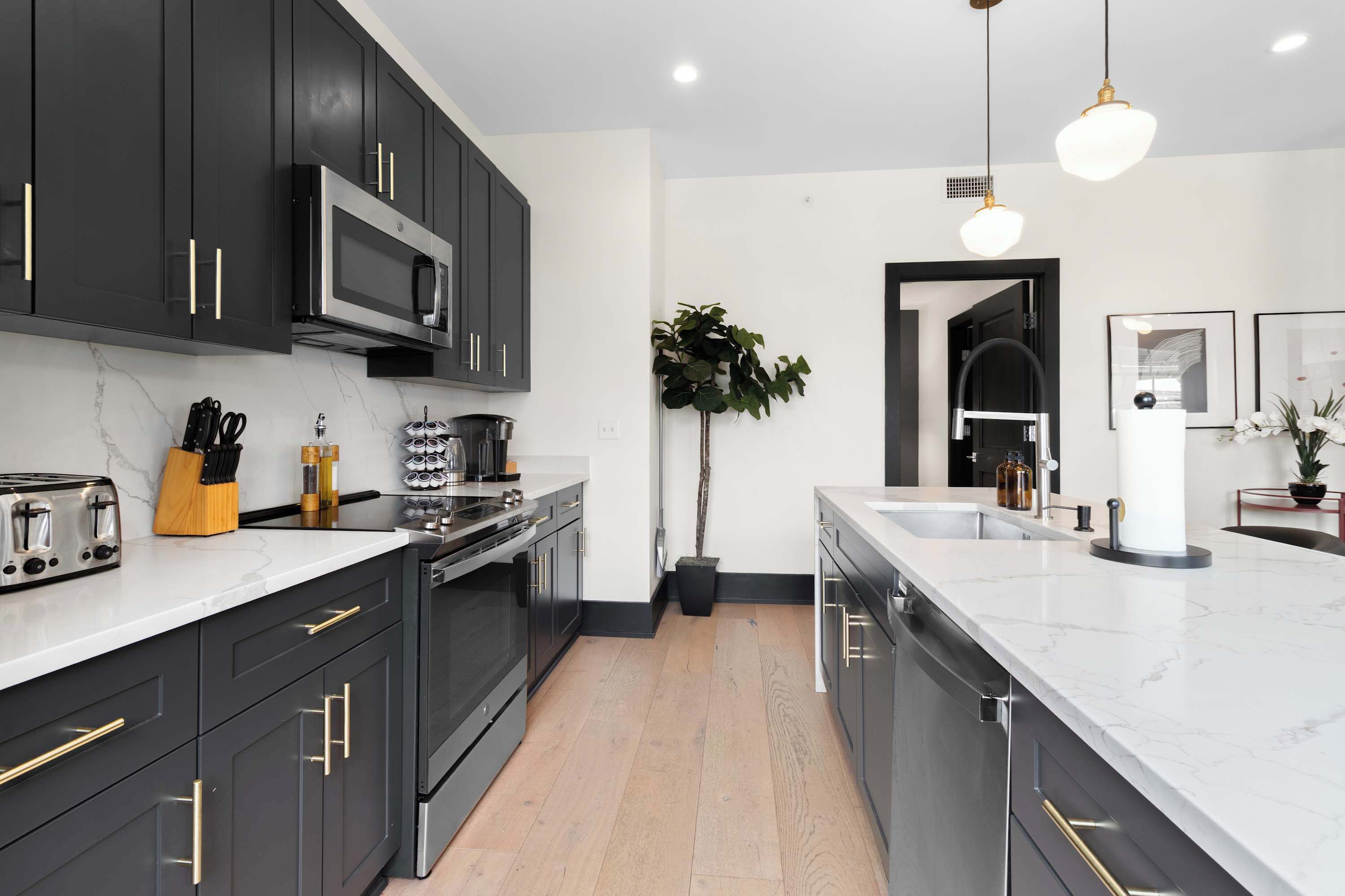 Une cuisine moderne avec des meubles de couleur sombre, une cuisinière en acier inoxydable et un grand îlot central doté d’un évier.