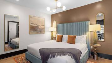 A hotel room with a large bed, two bedside lamps, a mirror, and a painting on the wall.