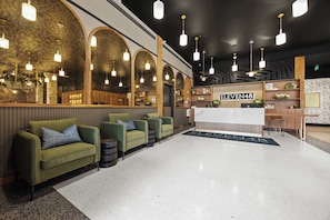 A hotel lobby with green sofas, a reception desk, and a sign reading 'ELEVEN48'. - Luxury 3BR Suite W/ Queen Sofa (New Orleans)