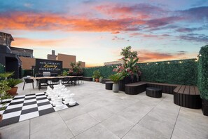 An outdoor patio area with a chessboard, seating, and a sign for 'New Orleans Luxury Collection.' - Luxury 3BR Suite W/ Queen Sofa (New Orleans)