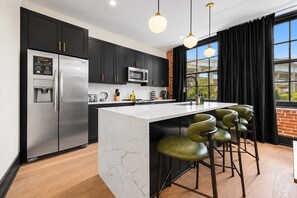 A modern kitchen with a central island, stainless steel appliances, and a black and white color scheme. - 3BR Suite W/ Queen Sofa Hotel (New Orleans)
