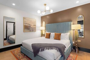 A hotel room with a large bed, two bedside lamps, a mirror, and a painting on the wall. - 2 KING BEDS + SLEEPER SOFA + ROOFTOP + GYM + GAMES (New Orleans)