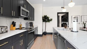 Een moderne keuken met donkere kastjes, een RVS-kookplaat en een groot eiland met een spoelbak.