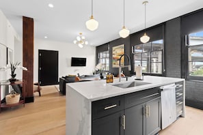 A modern kitchen with a large island, black cabinetry, and pendant lighting. - 2 KING BEDS + SLEEPER SOFA + ROOFTOP + GYM + GAMES (New Orleans)